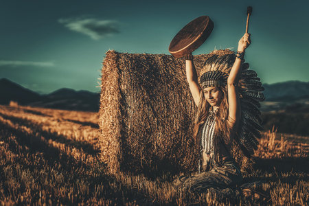 beautiful shamanic girl playing on shaman frame drum in the nature.の写真素材
