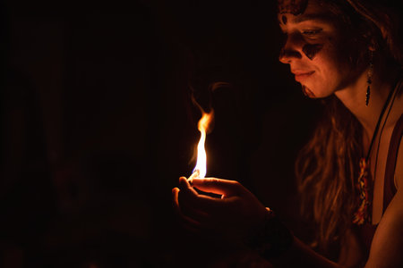 Meditating woman with palo santo in her hand. Woman is painted on her face with cocoa, cocoa...