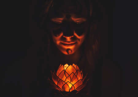 Meditating woman with lotus candle in her hand. Woman is painted on her face with cocoa, cocoa ceremony.の写真素材