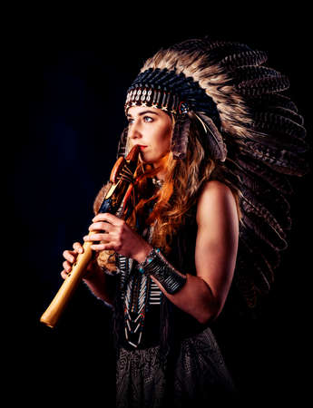 beautiful shamanic girl playing on shaman flute in the studio.の写真素材