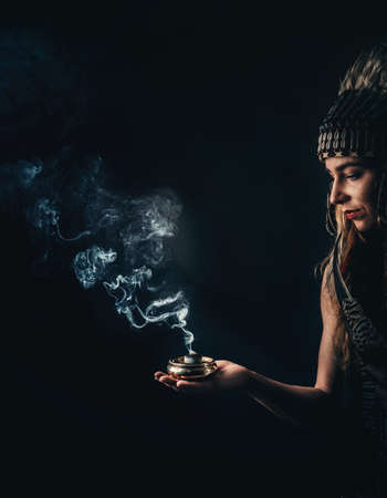 incense in a woman hand, incense smoke on a black background.の写真素材