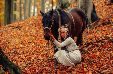Shaman woman in autumn landscape with her horse.の写真素材