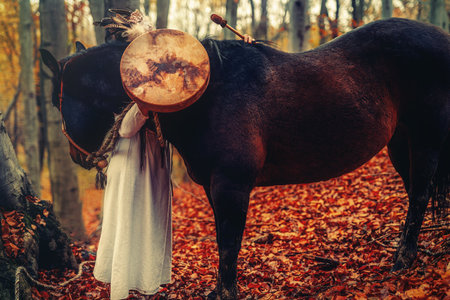Shaman woman in autumn landscape with her horse.の写真素材
