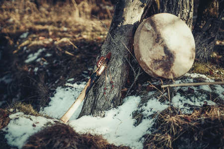 Shaman drum and flute in forest on tree. Winter landscape.の写真素材