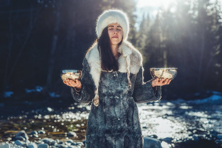 Beautiful shamanic girl playing on tibetian bowl in the nature.の写真素材