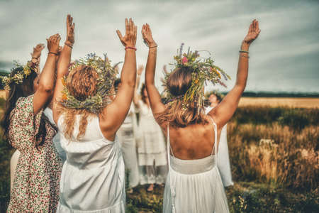 Women in flower wreath on sunny meadow, Floral crown, symbol of summer solstice.の写真素材