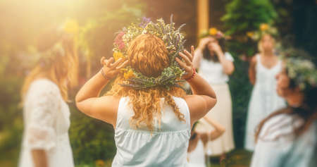Women in flower wreath on sunny meadow, Floral crown, symbol of summer solstice.の写真素材