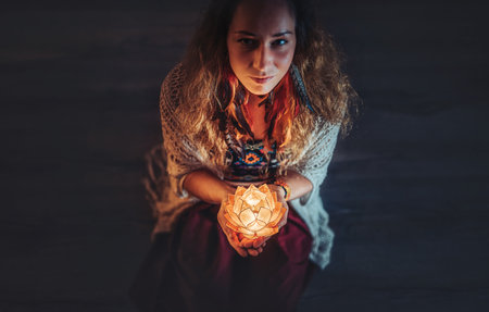 beautiful meditating woman with lotus candle in her hand.の写真素材