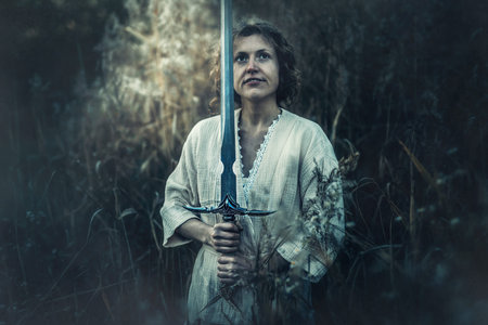 Beautiful woman in nature with a sword in her hand.