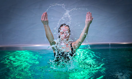 Beautiful woman splashing water in swimming pool.の写真素材