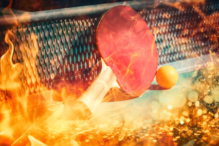 details of table tennis racquet on table with playing equipment and yellow ball. Fire effect.の写真素材