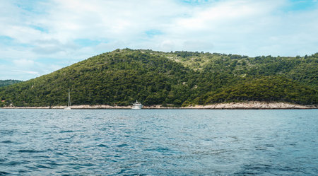 yacht at sea with an island in the background.の写真素材