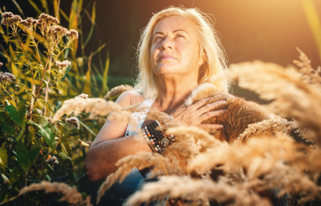 A Radiant Woman Stands Gracefully Among Golden Grasses at Sunset, Capturing Beauty and Calmnessの写真素材