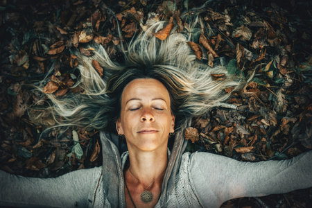 A Woman Joyfully Embracing the Beauty of Nature While Surrounded by Autumn Leavesの写真素材