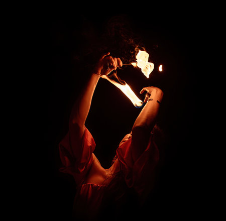 An enchanting fire dancer beautifully showcases her talent with mesmerizing flames during a performance.の写真素材