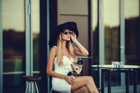 portrait of a romantic and stylish blonde with Yorkshire Terrier at the hotelの写真素材
