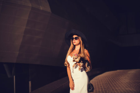Glamorous lady in a hat with a small dogの写真素材