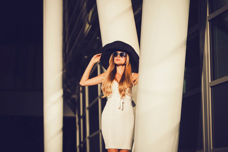 portrait of the blonde woman in white dress and hat near the hotel. journeyの写真素材