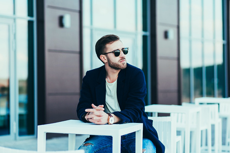 Casual man wearing sunglasses and jeans posing in cityの写真素材