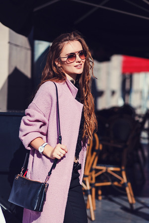 Portrait of cute girl with long curly hair and smiling in cityの写真素材