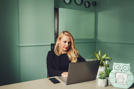 Beautiful office woman sitting on table with laptopの写真素材