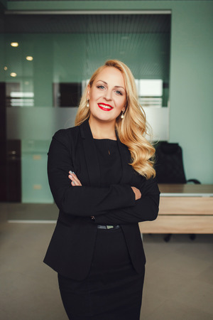 Portrait of young laughing business woman in the office. Crossed armsの写真素材