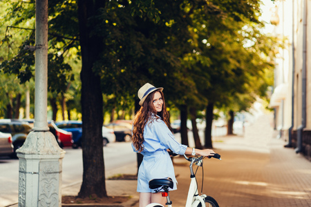 Stylish girl in a hat with a bicycle on the sidewalkの写真素材