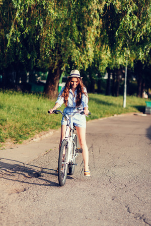 Young woman riding bicycle in hatの写真素材