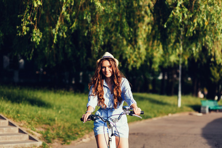 Young pretty woman posing on the nature with bike in summer sunshine.の写真素材