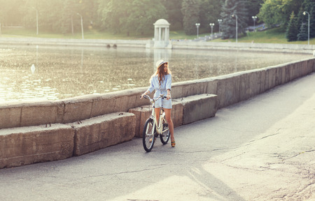 beautiful young woman standing next to her bike outdoorsの写真素材