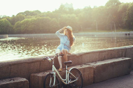 Beautiful woman in a park with a bicycle sunset. Tourismの写真素材