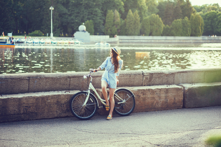Romantic woman with vintage bicycle by the river looking awayの写真素材