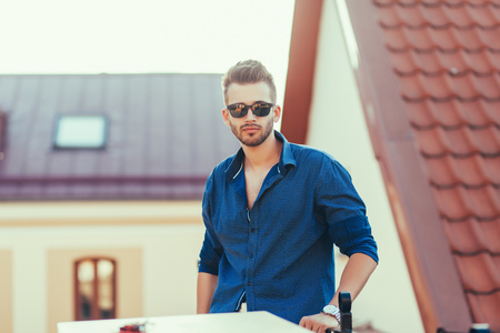 Stylish man standing in street wearing shirt and sunglasses, portraitの写真素材