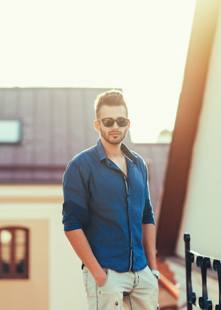 Handsome man posing in the city in a summer blue shirtの写真素材