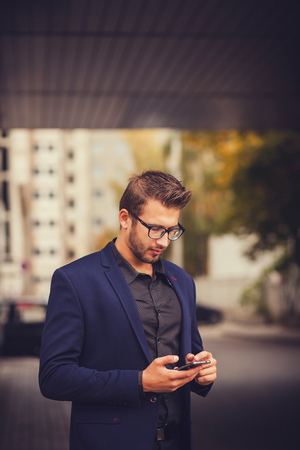 Entrepreneur uses phone mobile smart. Young handsome businessman in cityの写真素材