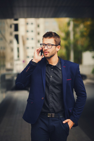 business man with glasses and a suit talking on the phoneの写真素材