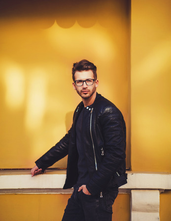 Portrait of a smart young man standing against yellow backgroundの写真素材