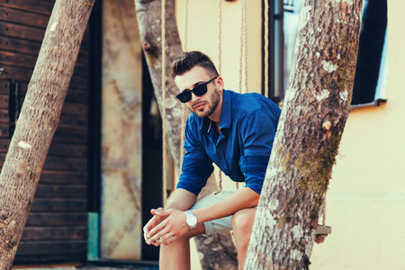 Sexy man in stylish clothes sitting near the beachの写真素材