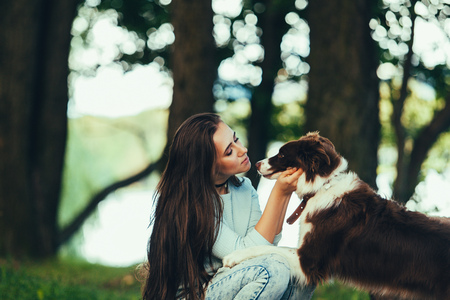 Beautiful woman kissing her dog. Outdoor portrait.の写真素材