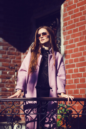 Portrait of young girl wearing coat outdoors. Pretty russian female with long wavy hair hairstyle. Woman in urban background.の写真素材