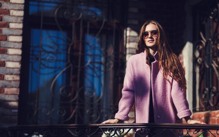 Fashionable girl walking on street wearing sunglasses and jacket. copyspaceの写真素材