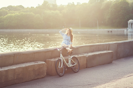 woman riding vintage bicycle on park during sunset or sunrise. copyspaceの写真素材