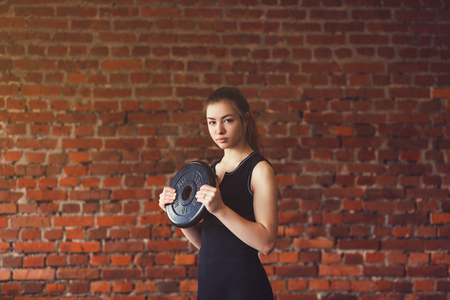 Young athlete exercising crossfit. Woman in sportswear doing crossfit workout on brick background.の写真素材