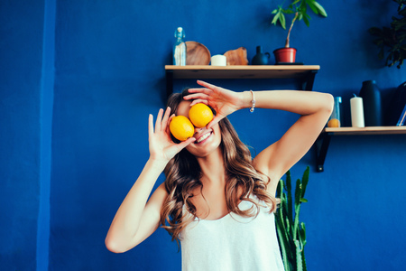 Young beautiful woman with orange on blue backgroundの写真素材