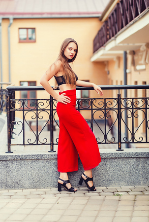 full-height portrait of a fashionable young woman in red pants in the cityの写真素材