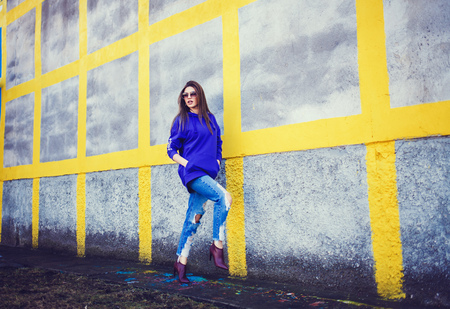 Young pretty fashion woman in sunglasses smiling and walking colorful wall.の写真素材