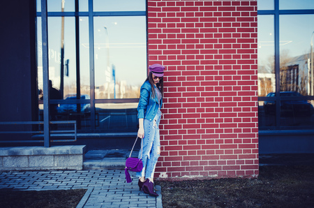 Full length portrait of trendy woman standing at the brick wall Background. Urban Fashion Concept. Copy Space.の写真素材