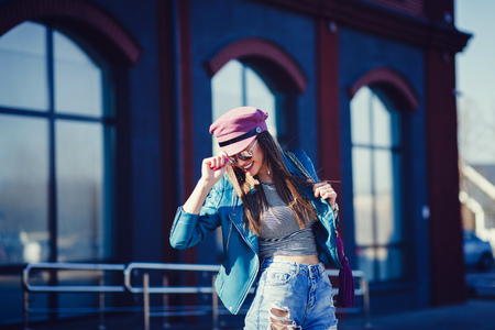 successful and happy woman in hat and leather jacket smiles in the cityの写真素材