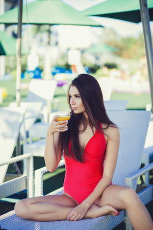Sexy woman with cocktail sitting on sunbedの写真素材