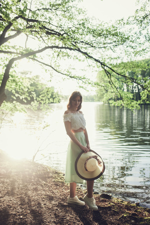 Outdoor photo of young woman in autumn park with hatの写真素材